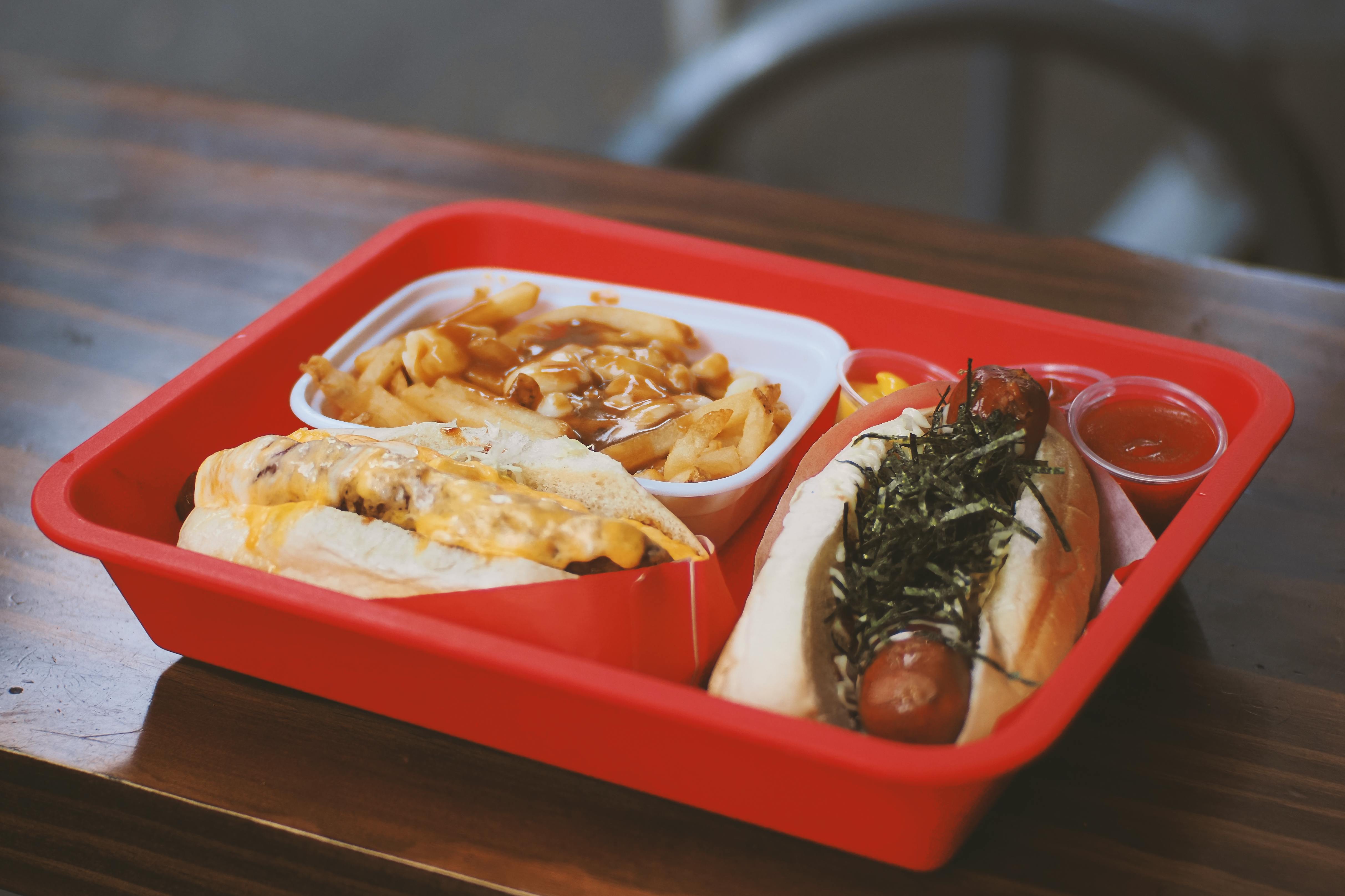 Authentic Vancouver Japadog and poutine served in a vibrant red tray, showcasing Japanese-Canadian fusion cuisine.
